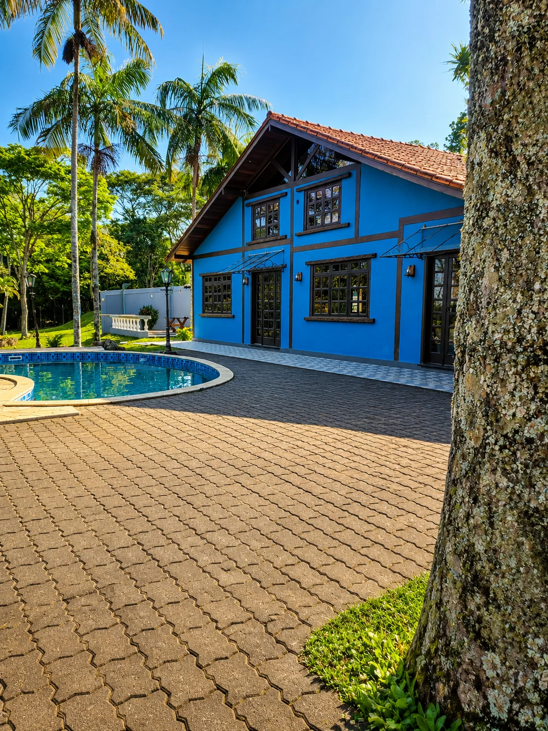 Foto real da fachada azul da Casa da Represa ao lado da piscina