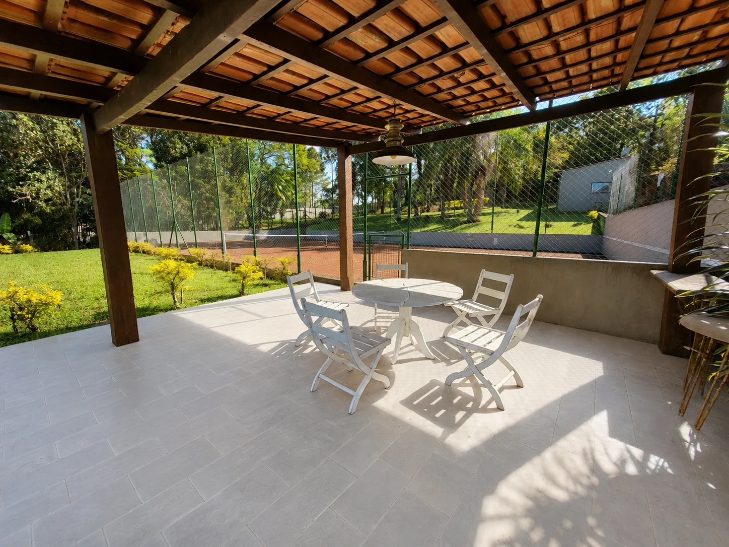 Varanda coberta com vista para a quadra e o jardim